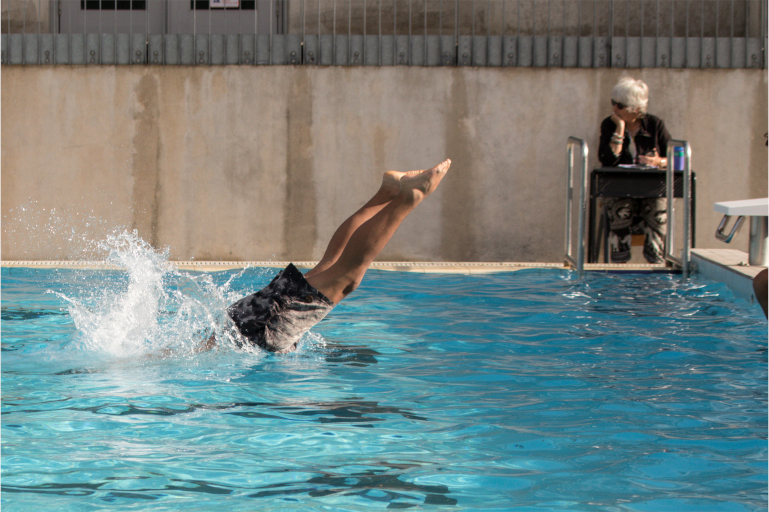 Side-on of student's legs sticking out of water after diving into swimming pool