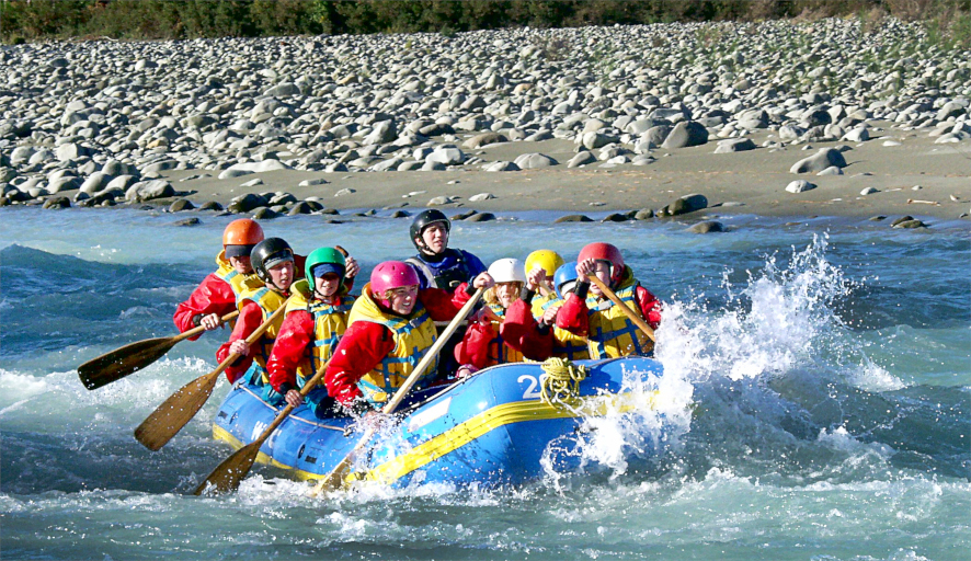 Seven students rowing in a rubber dingy with a coach